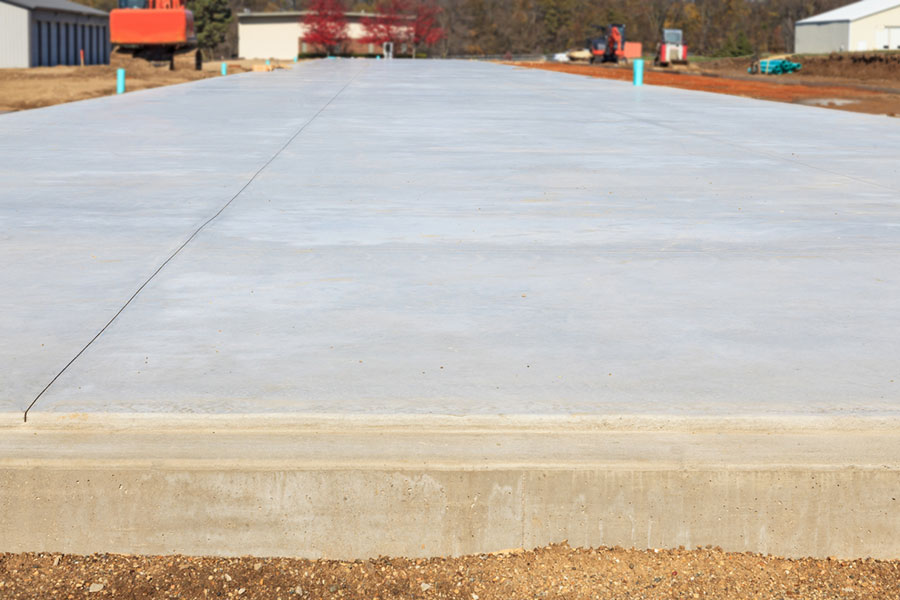 A large, newly poured concrete slab at a construction site, currently being prepared for a decorative patio.